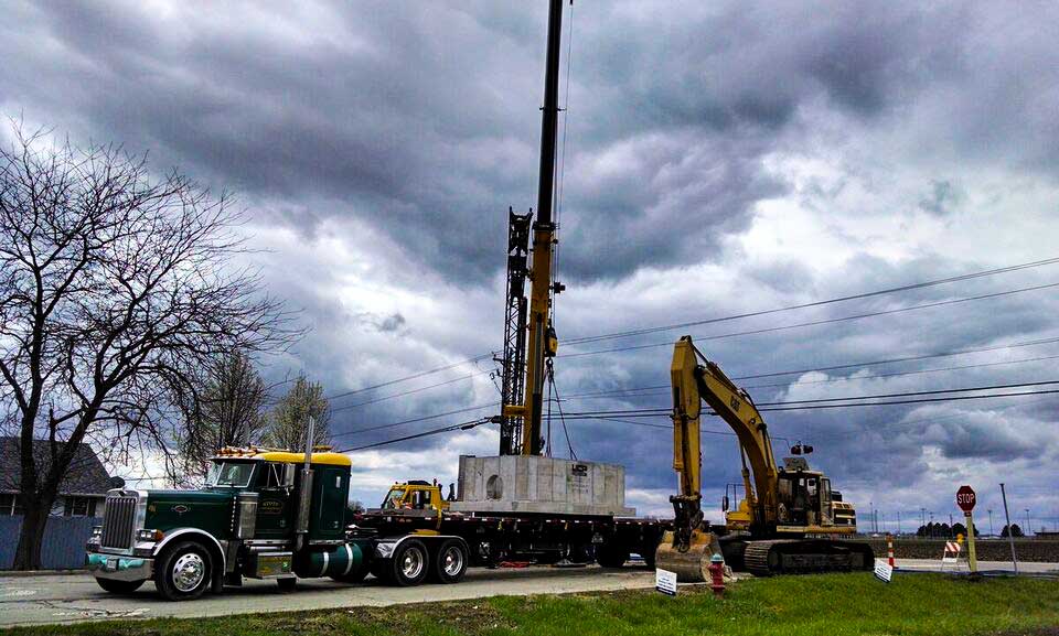 Semi truck delivering utility concrete base for piping project